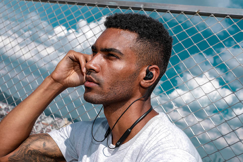 A man uses a black TRN V10 earphone with a wireless Bluetooth module