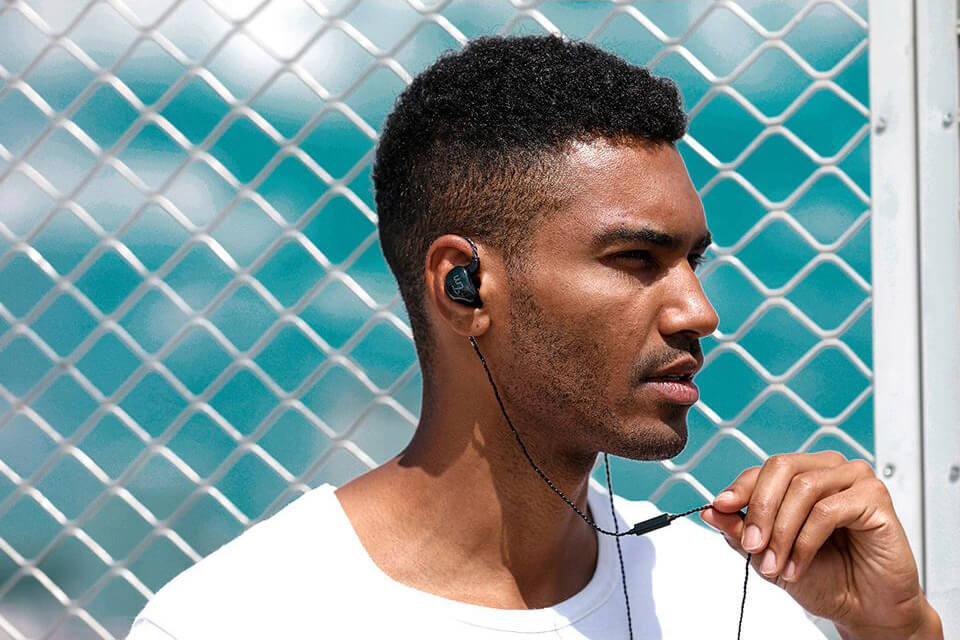 A man uses a glossy black TRN V10 earphone with a black cable