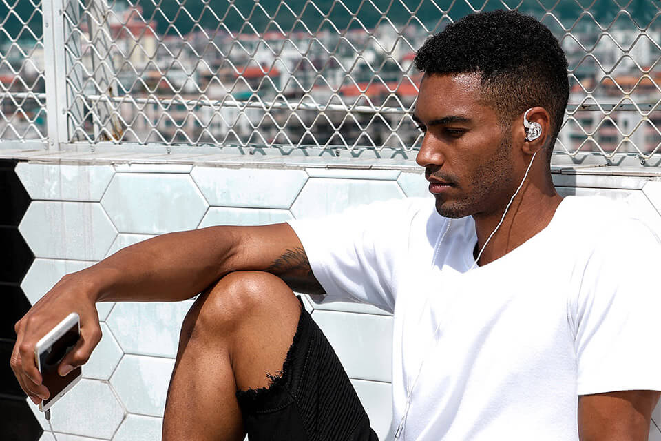 A man uses a clear TRN V10 earphone with a silver cable