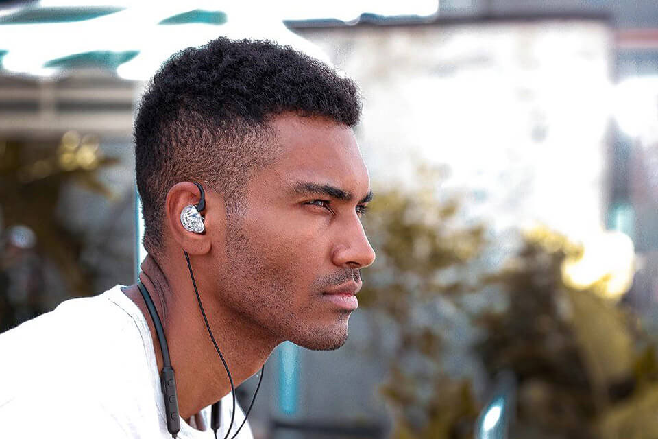 A man uses a clear TRN V10 earphone with a wireless Bluetooth module