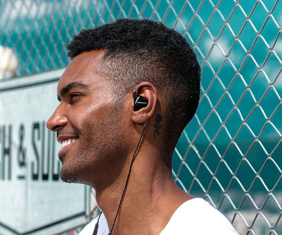 A joyful man uses a black TRN V20 earphone